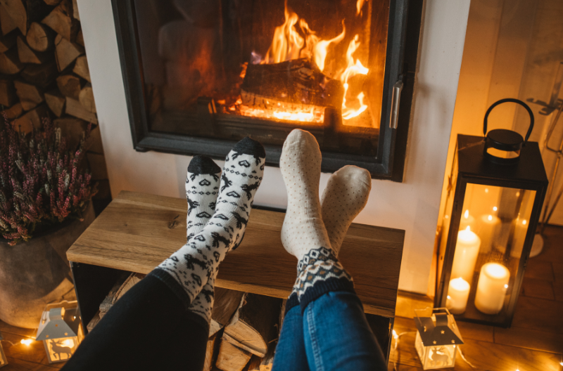 Two people sitting with their feet up in front of a fireplace.